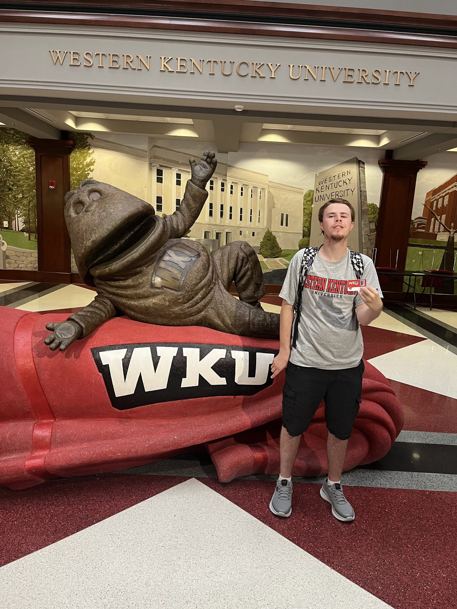 Student standing beside WKU statue