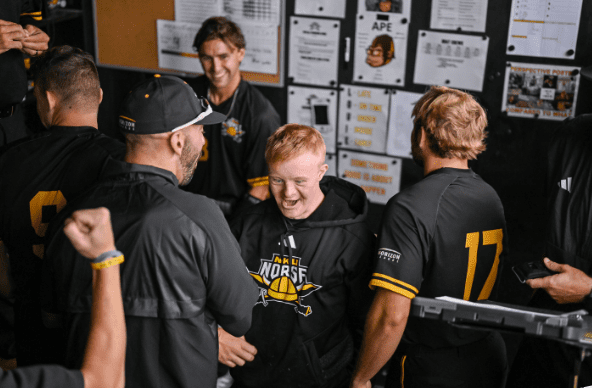 The NKU baseball team surrounds Joe in the locker room.