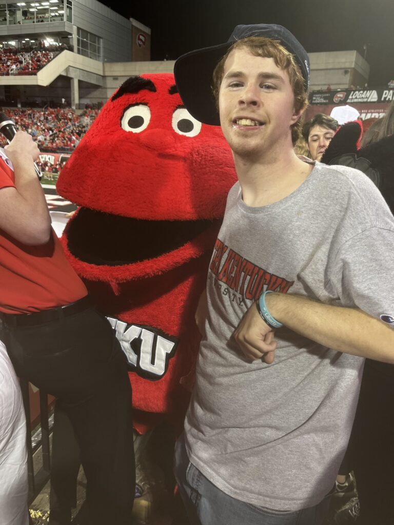 WKU Student standing beside the Hilltopper at a WKU football game
